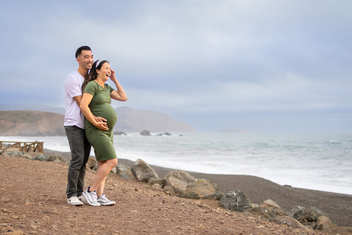 Bay Area Maternity Portfolio - Ellobelle Photography couple laughing together along ocean cliffs during maternity s