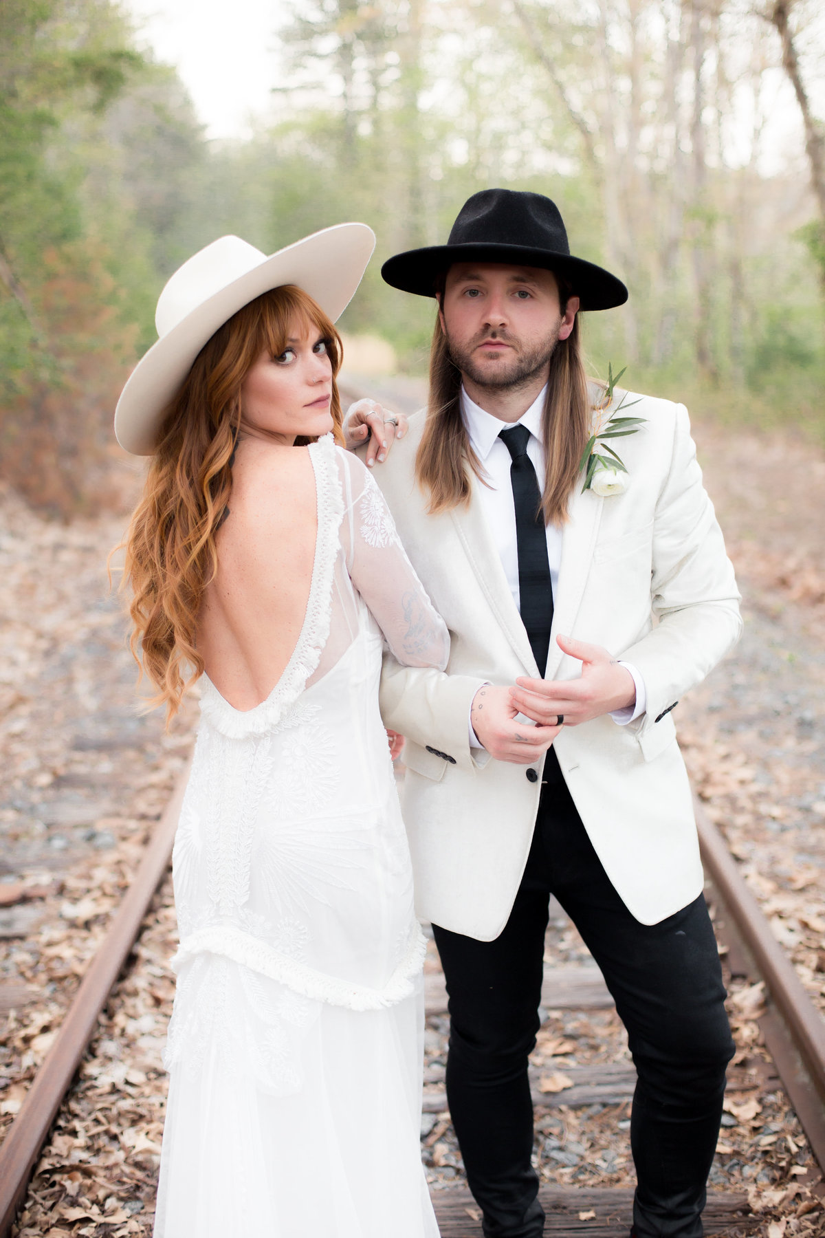 trendy  designer couple with hats pose for atlanta wedding photographer