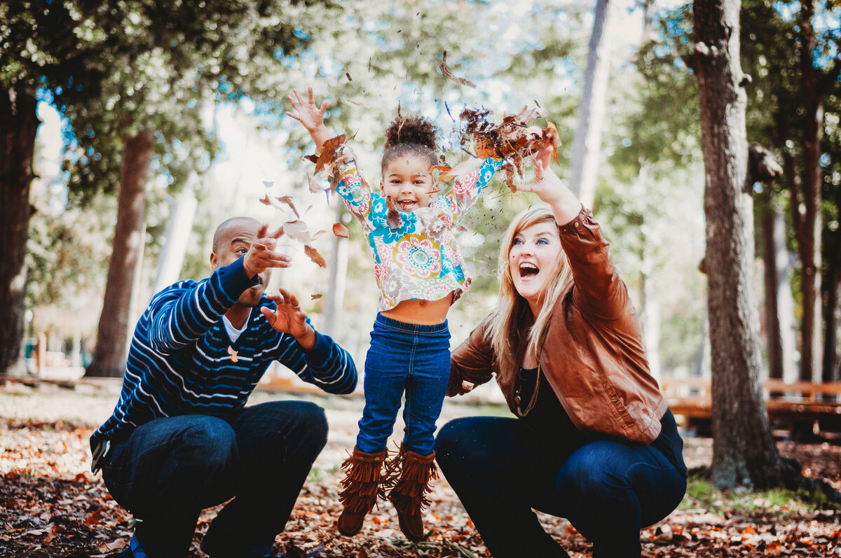 Family tossing leaves and playing together during a fall-themed family photo session in Winter Garden, Florida.
