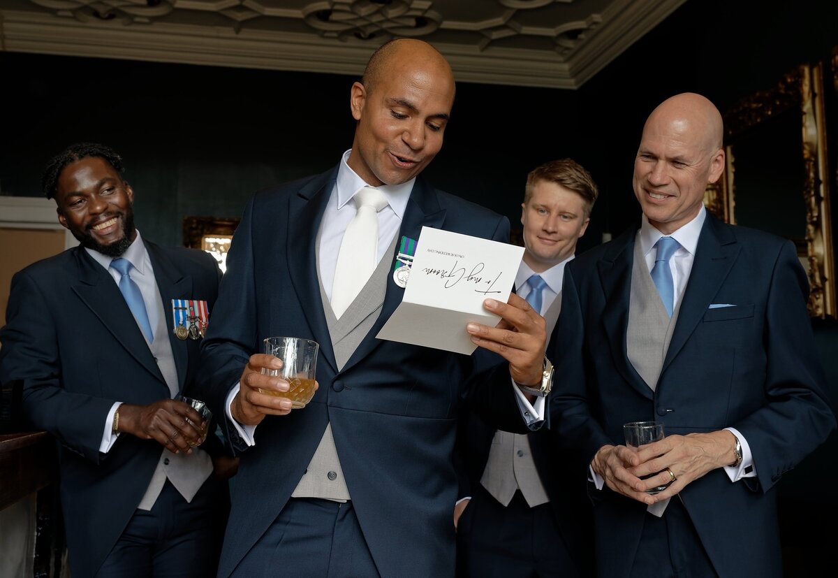 Groom and groomsmen reading a letter from his bride on the morning of their wedding