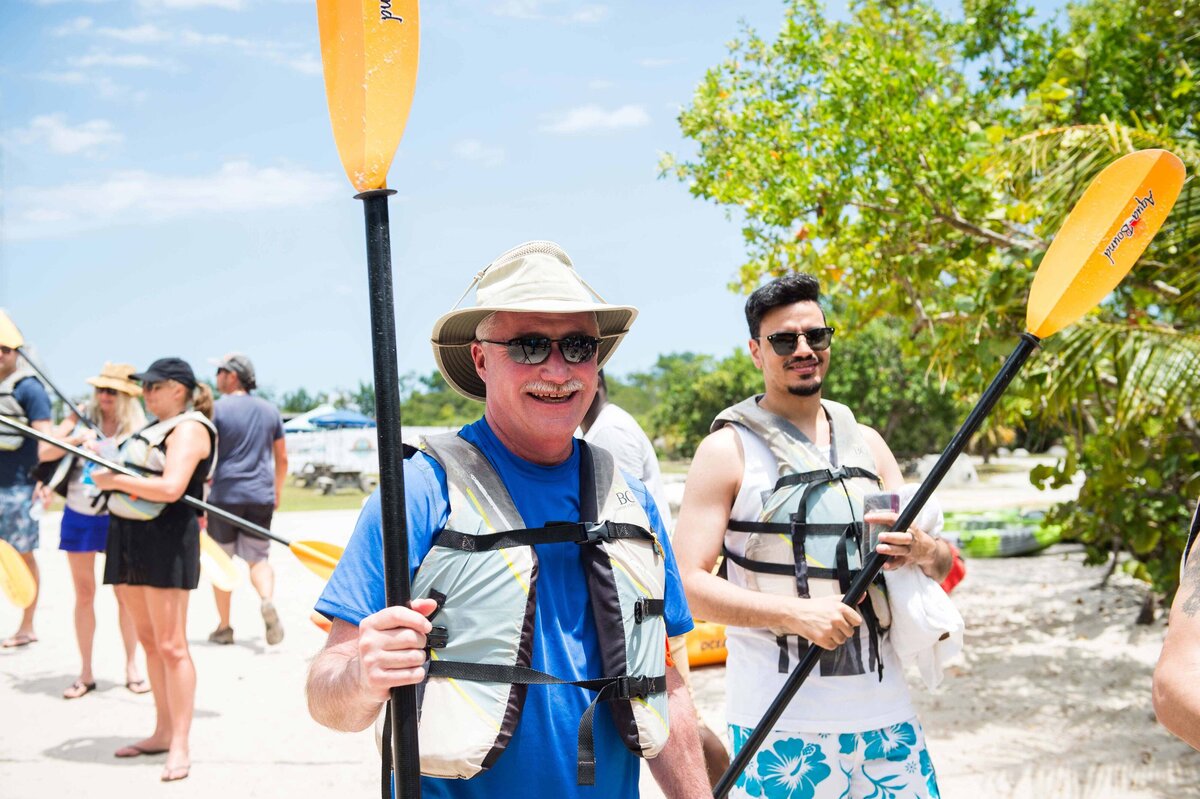 A man holds an ore as others walk to their kayaks for lagoon kayaking activity tour