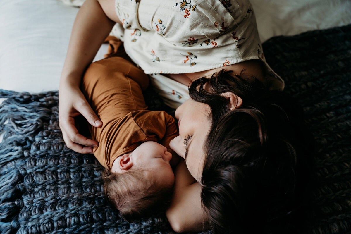 Newborn Photography, mom lays on the bed with her baby close beside her