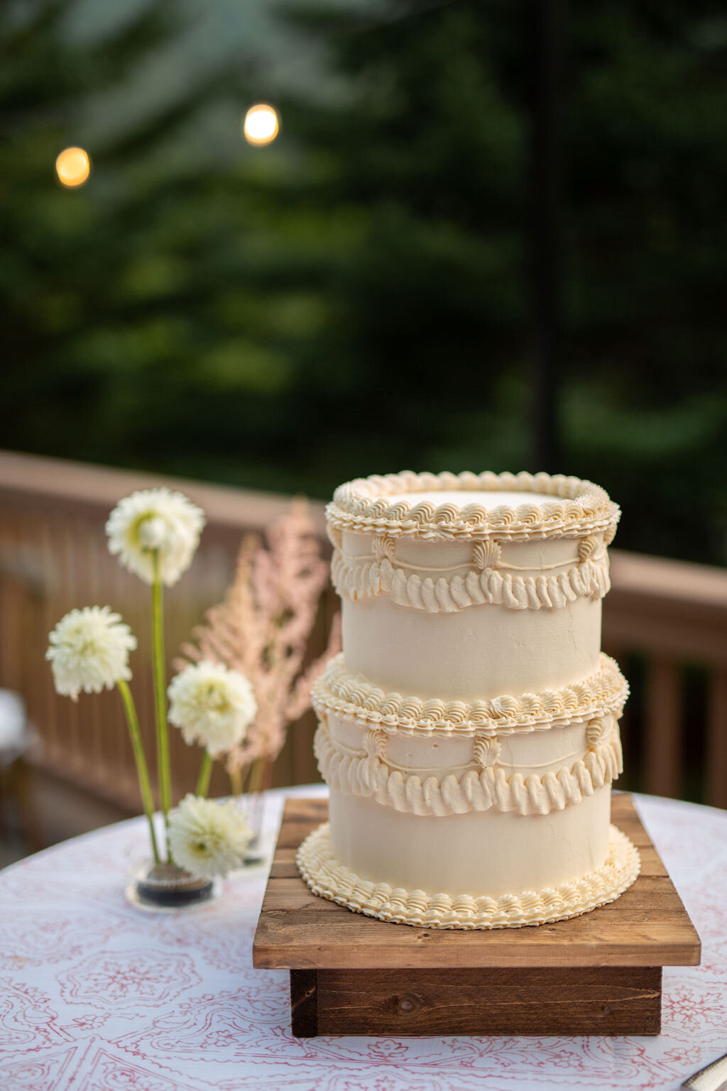 An elegant 2-tiered wedding cake on a table with white flowers.