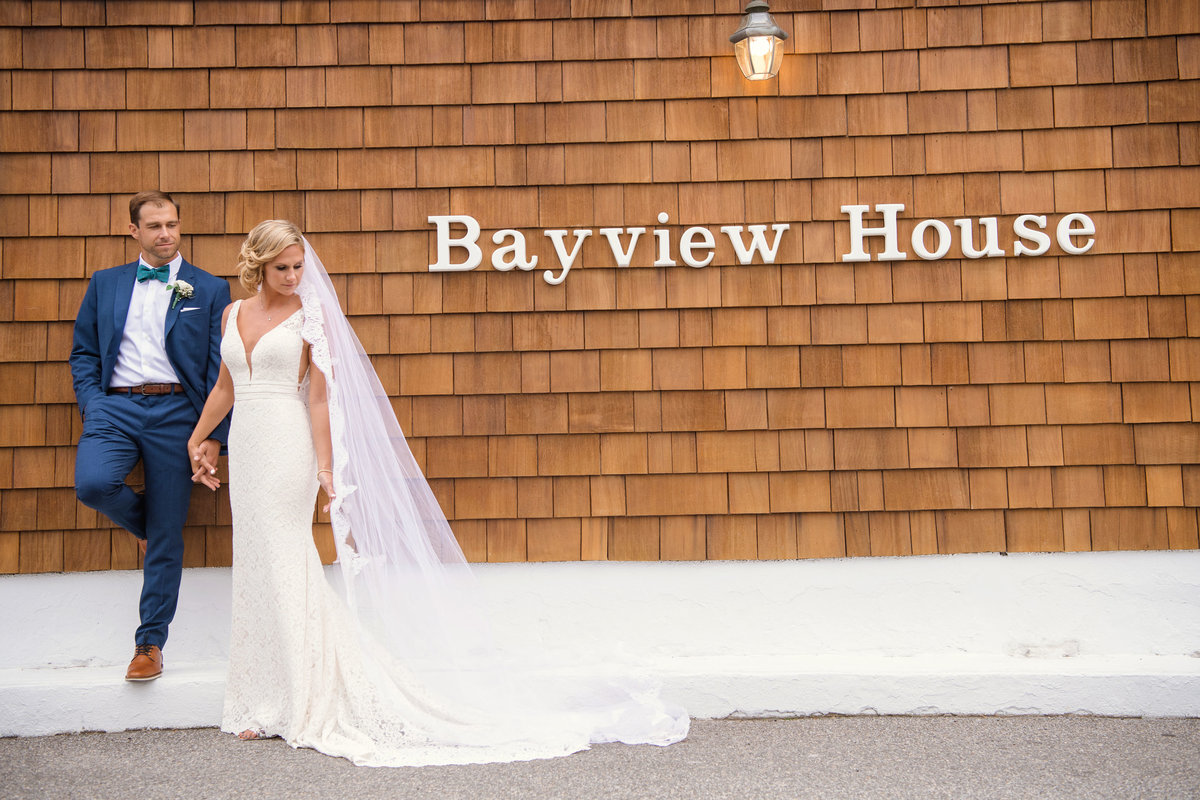 Bride and groom posing next to Bayview House at Captain Bills