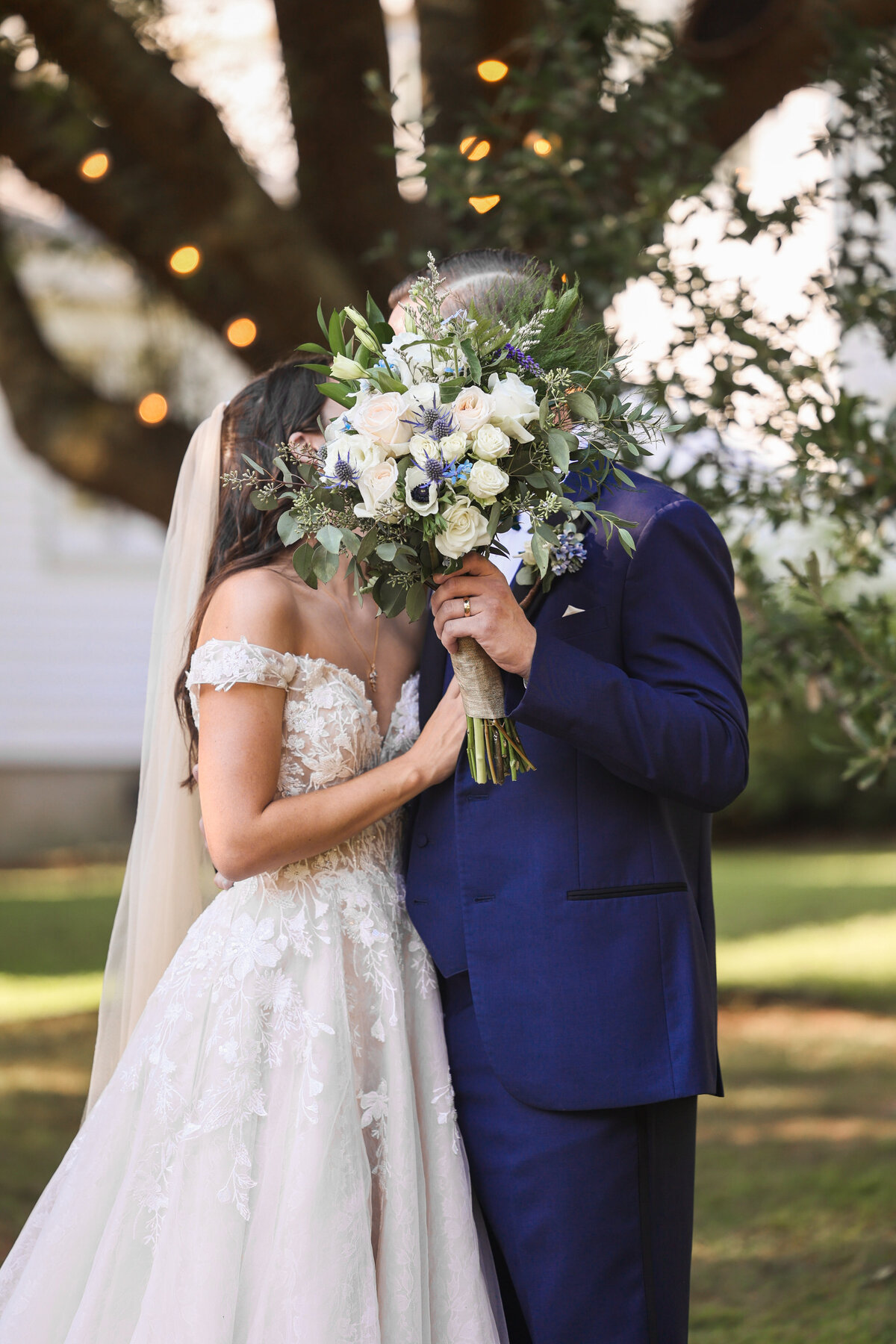 bride and groom holding bouquet and kissing behind flowers at Correy House in Union Point Georgia by Amanda Richardson Photography