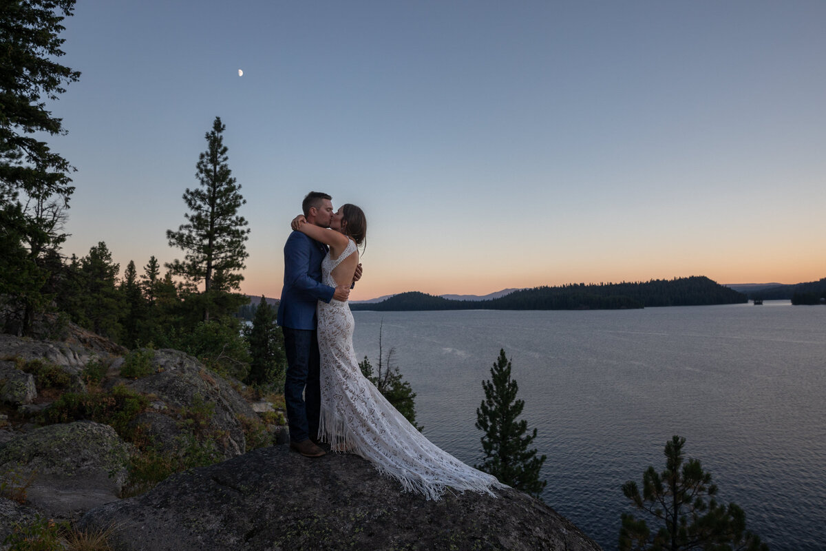 A bride and groom share an embrace and a kiss as the sunsets.