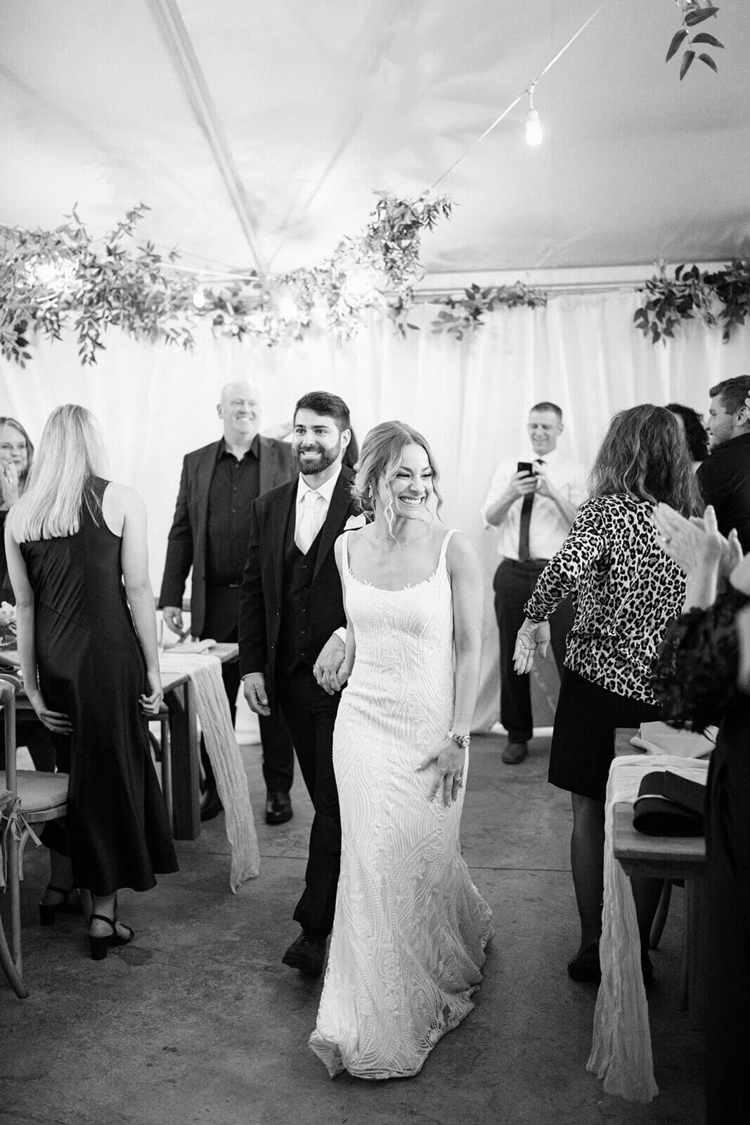 Bride and groom walking through wedding reception