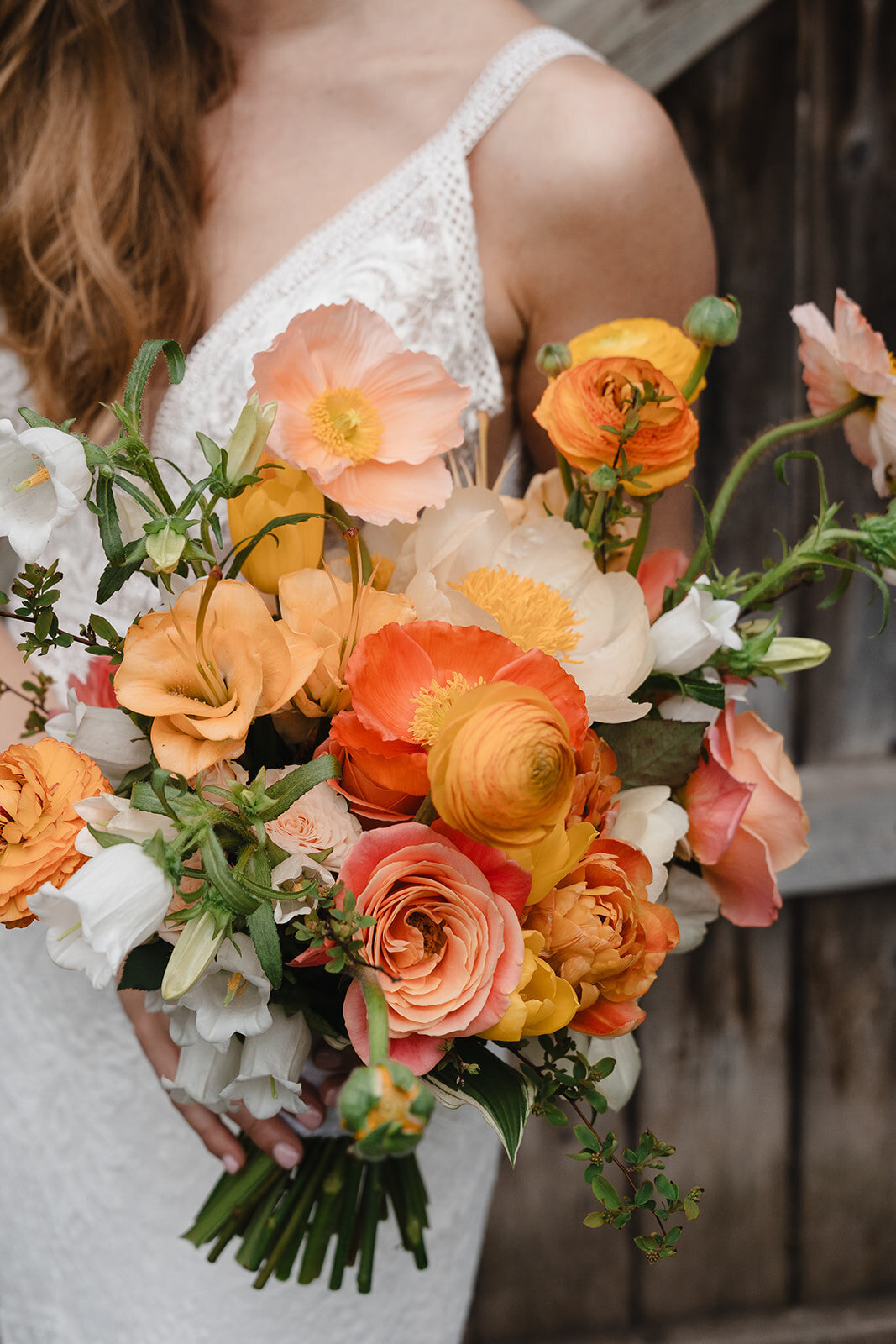 A bride holds a bouquet of bright peach and orange flowers at a wedding in Montreal.