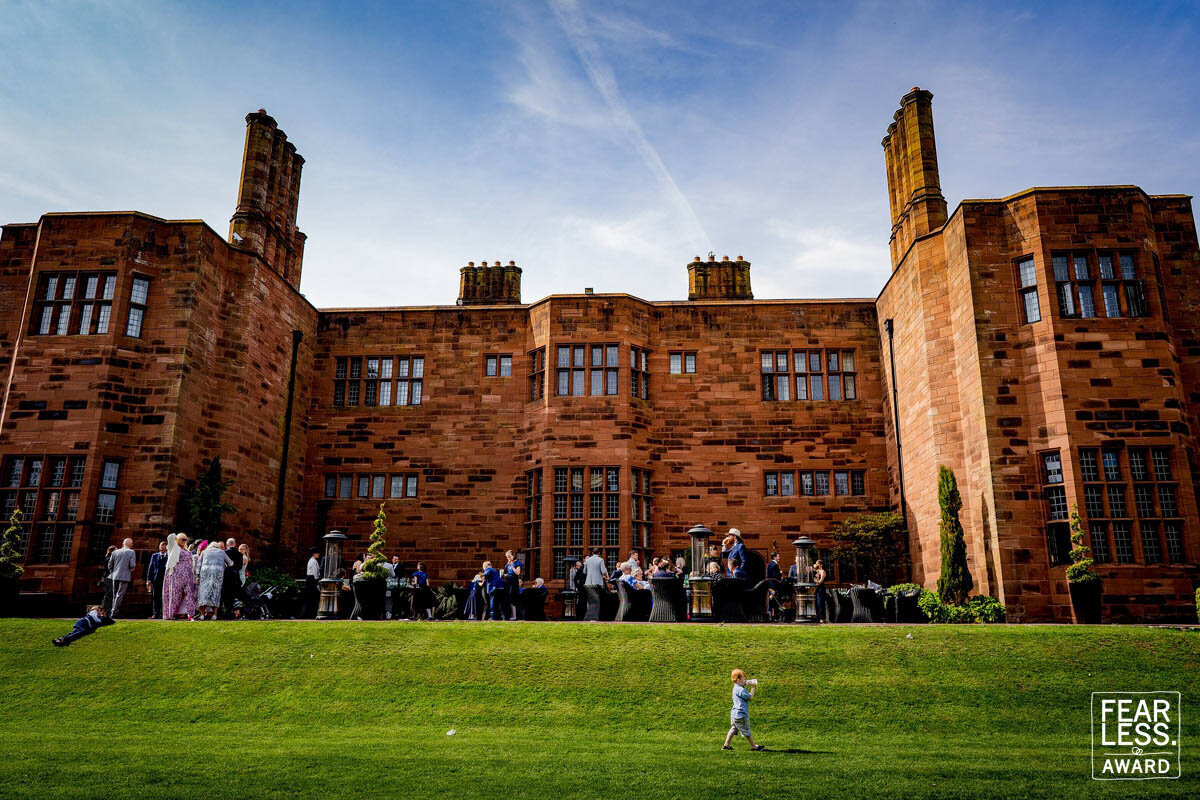 photography at abbey house in the lake distrtc of a groupd og guests with a flower boy walking in the foreground