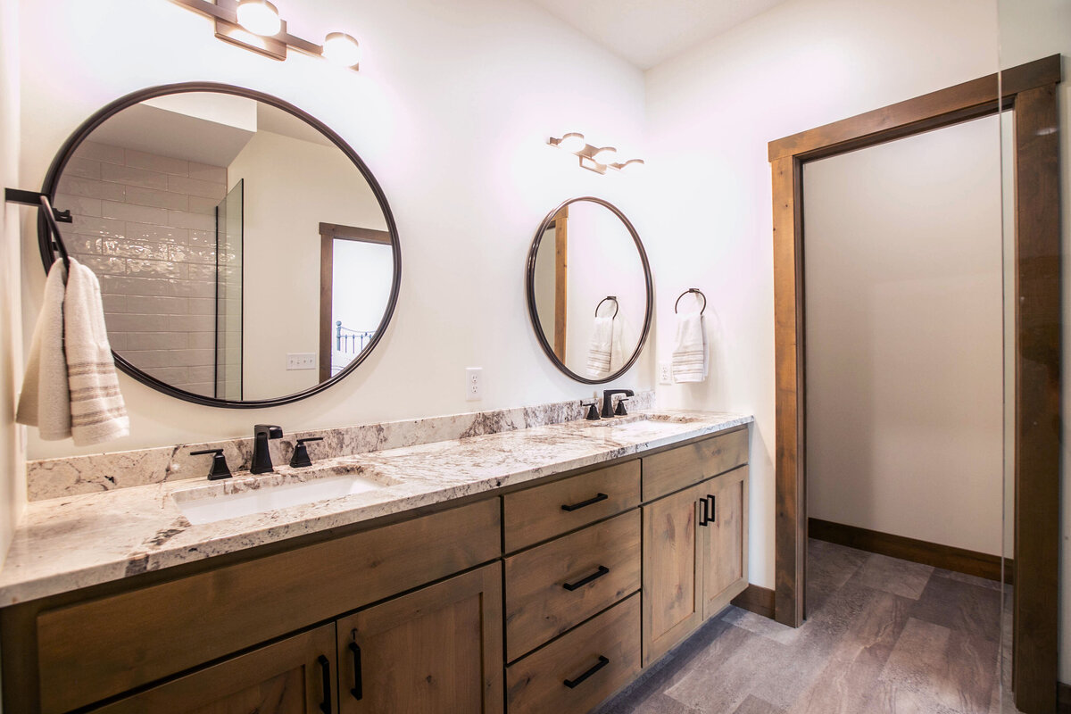 Custom bathroom with dark cabinets, double vanity, and walk-in shower in Elk River custom home