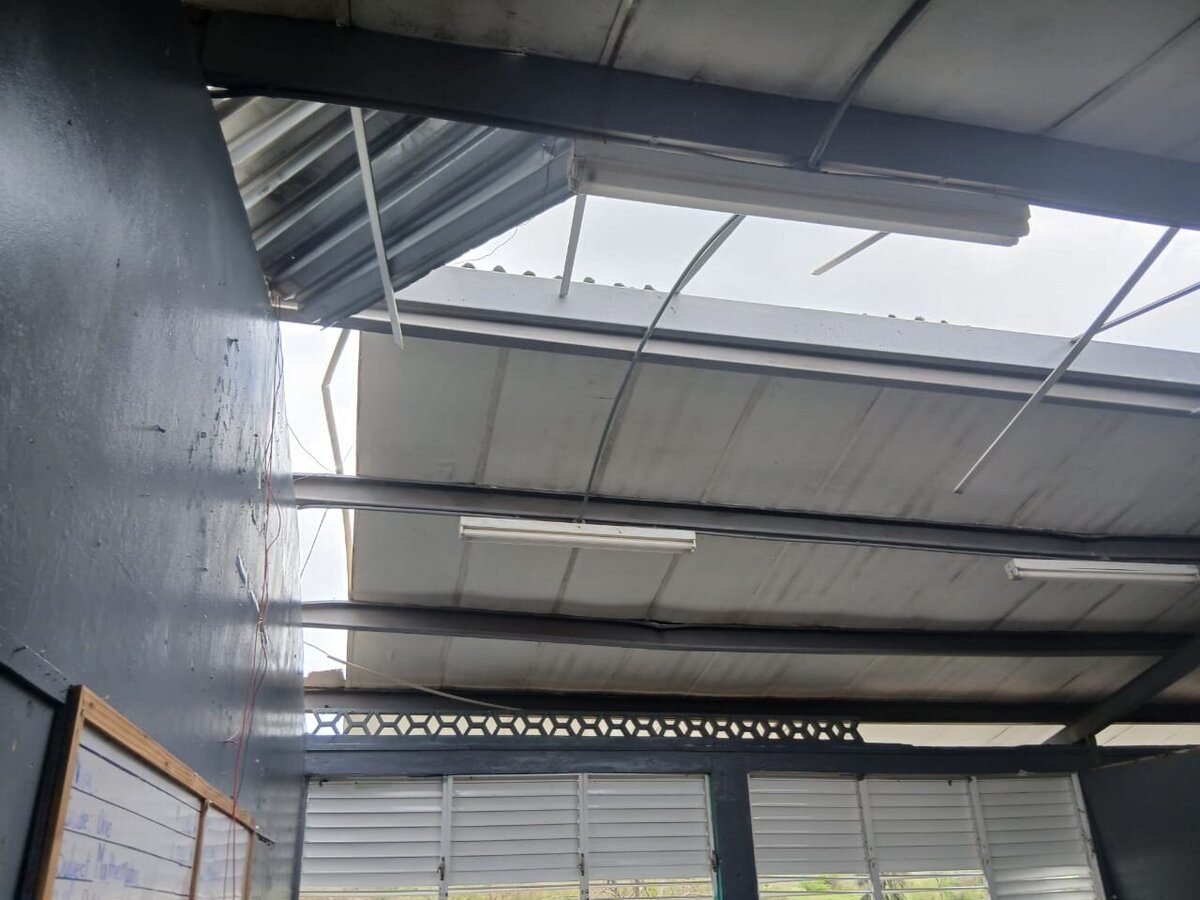 Open ceiling with bent metal beams and roof loss at Barbary Hall Primary after the hurricane.
