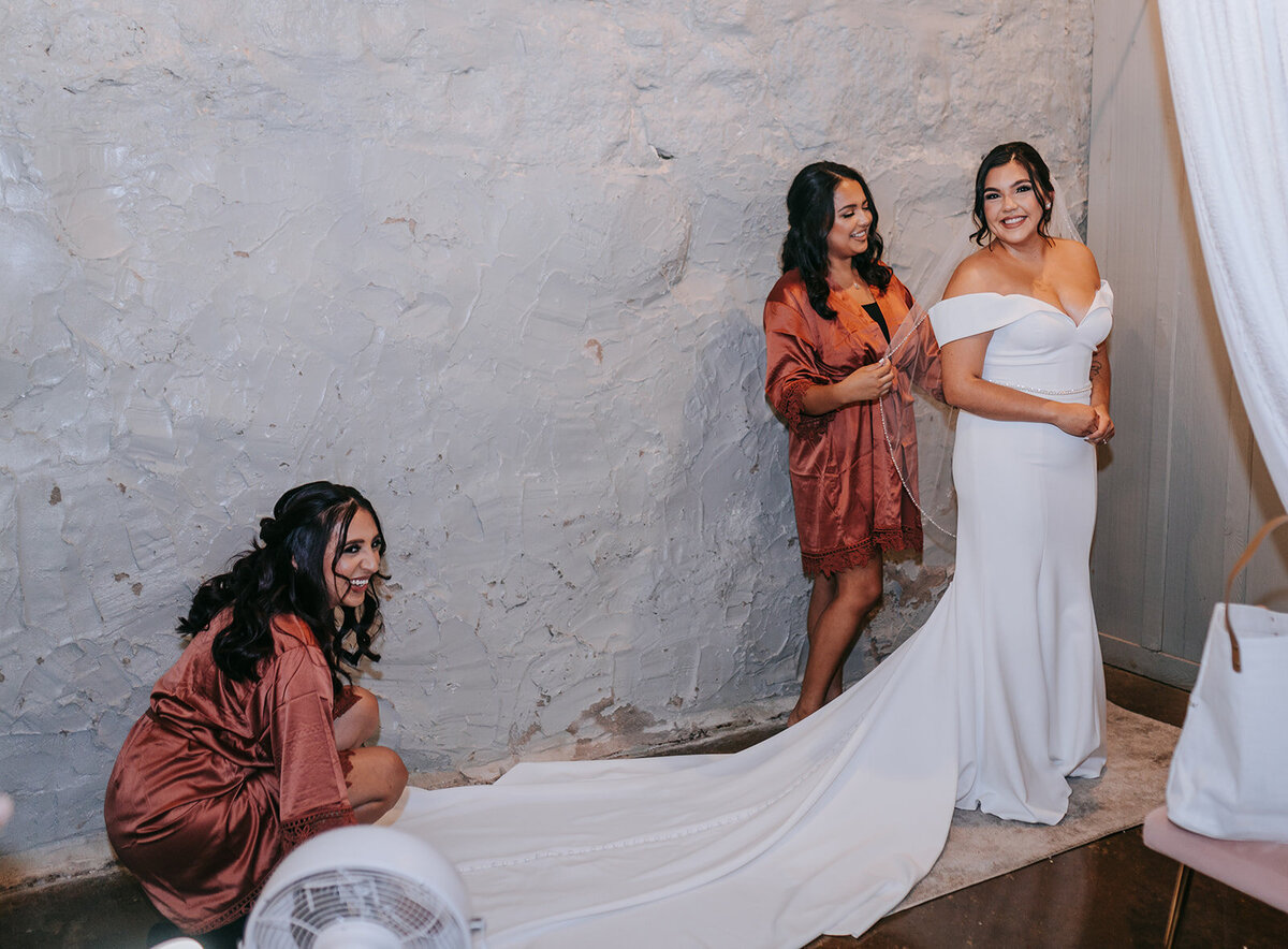 Bridesmaids helping bride fix her wedding dress
