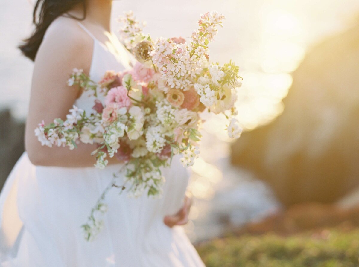 San Francisco maternity photography session on the coast with a woman wearing a white dress with a bouquet