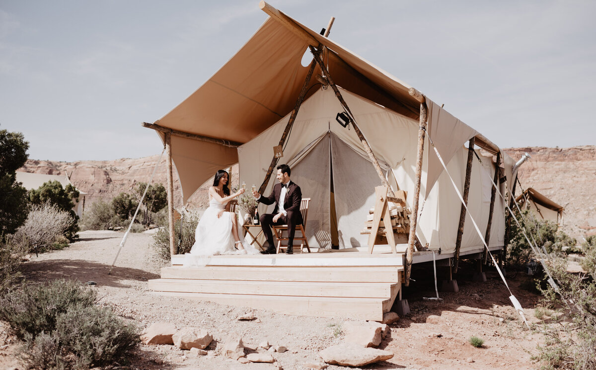 Utah elopement photographer captures bride and groom pouring champagne in front of airbnb