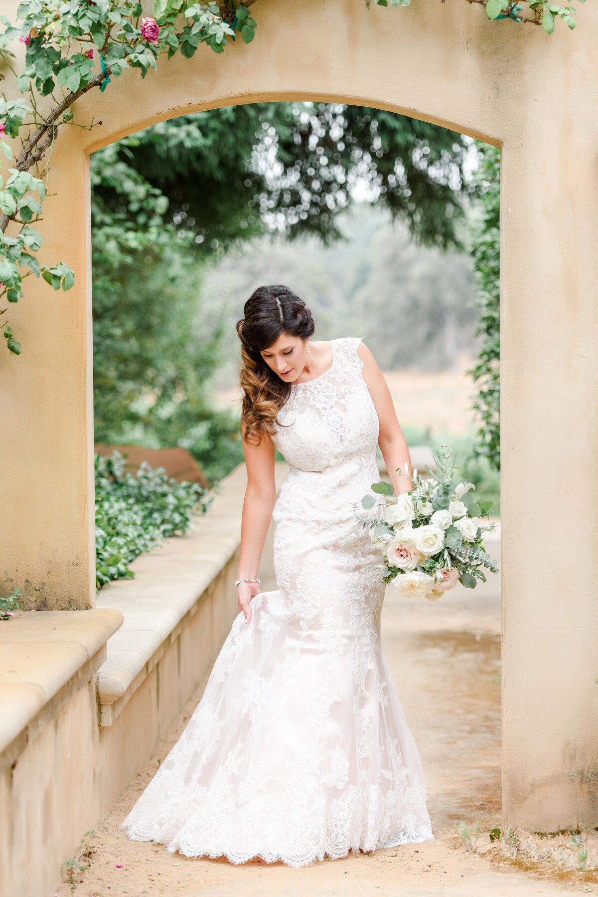 a bride standing under a arch of roses