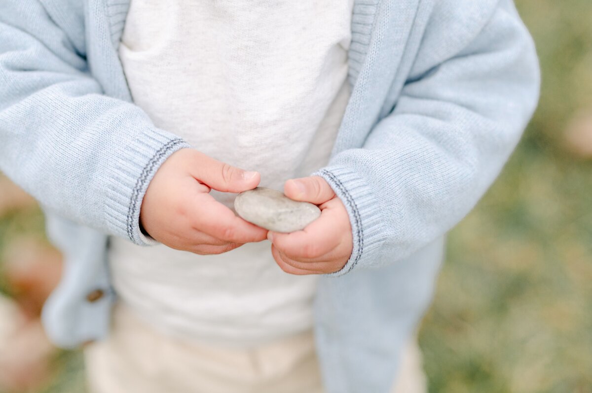 Close up photograph of a toddler's hands holding a smooth gray stone