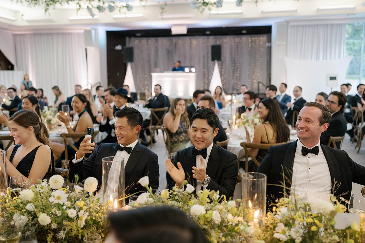 Guests clap, cheer, and take photos during the wedding speeches at the Aspen Meadows Resort reception venue.