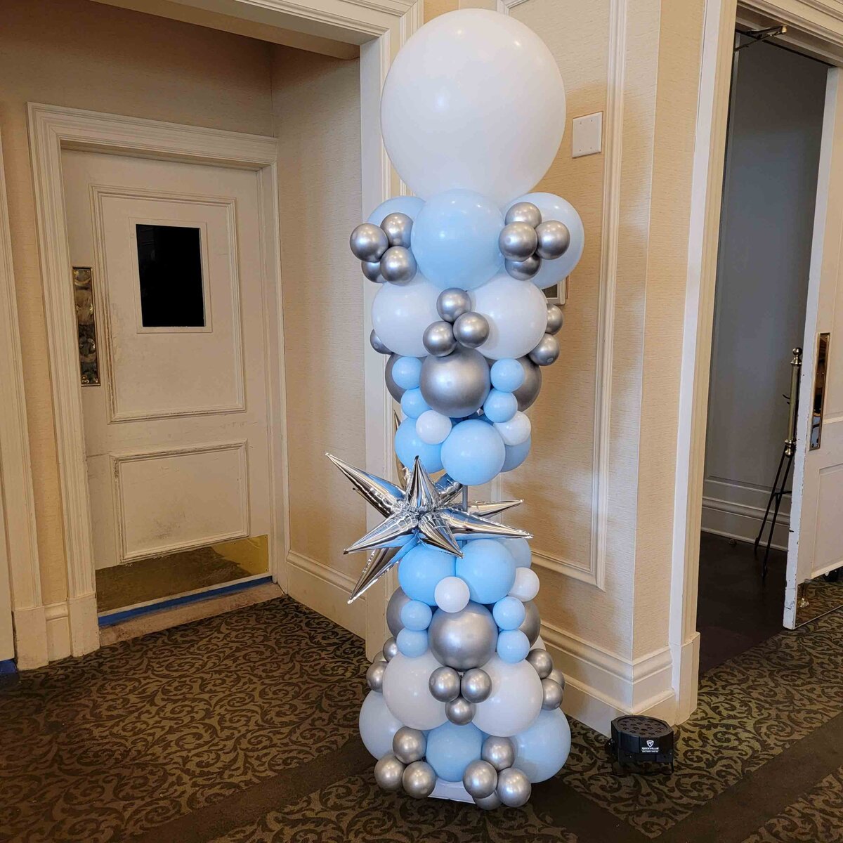 The event with air with flair decor's balloon columns, featuring the elegance of silver, blue, and white star vibes.
