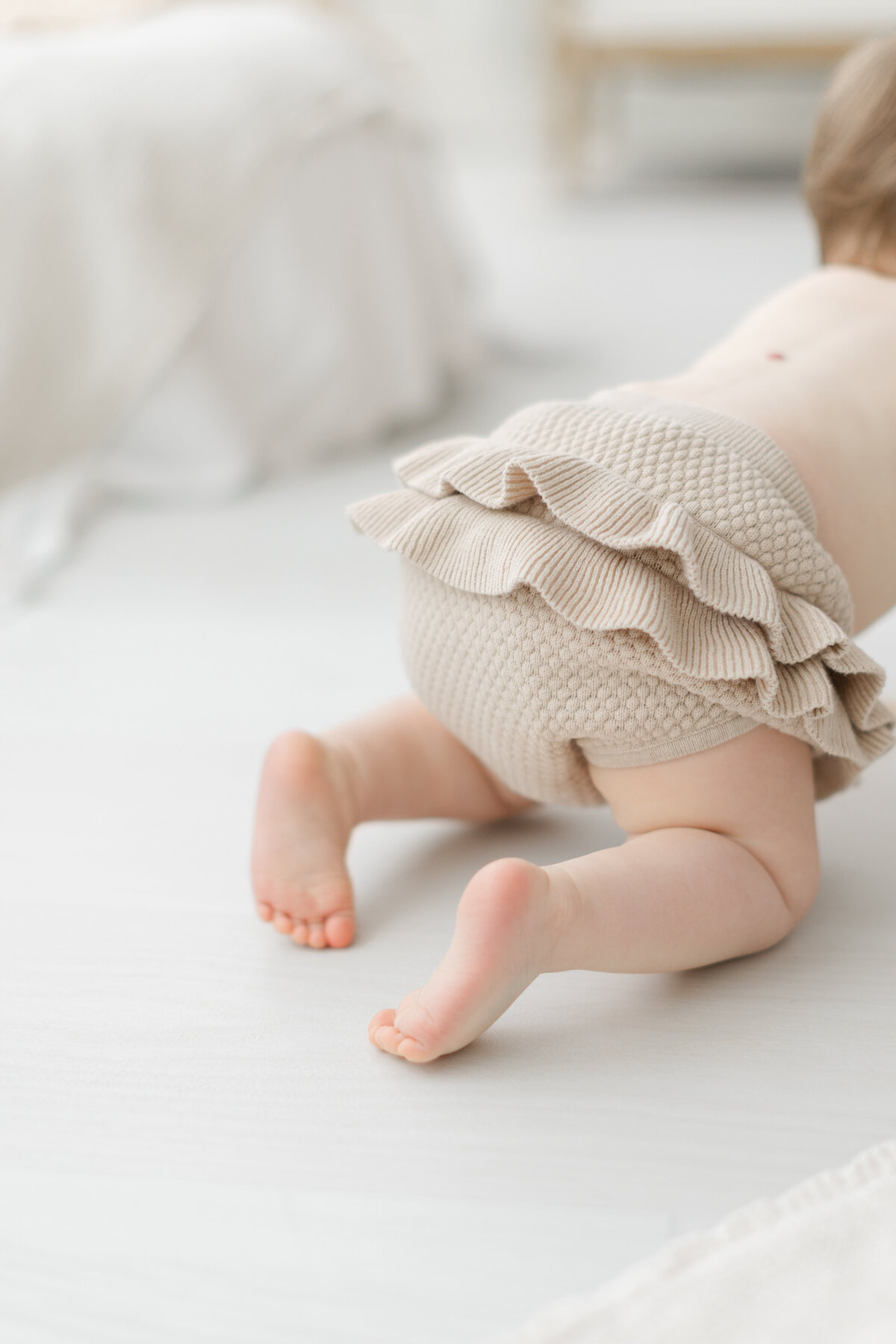 Baby crawls away wearing ruffled-bottom diaper cover