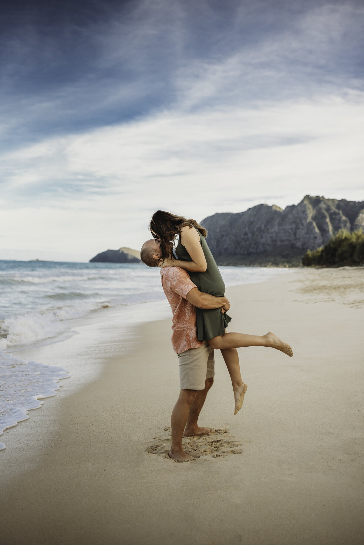 Man lifting up woman while they kiss on a beach