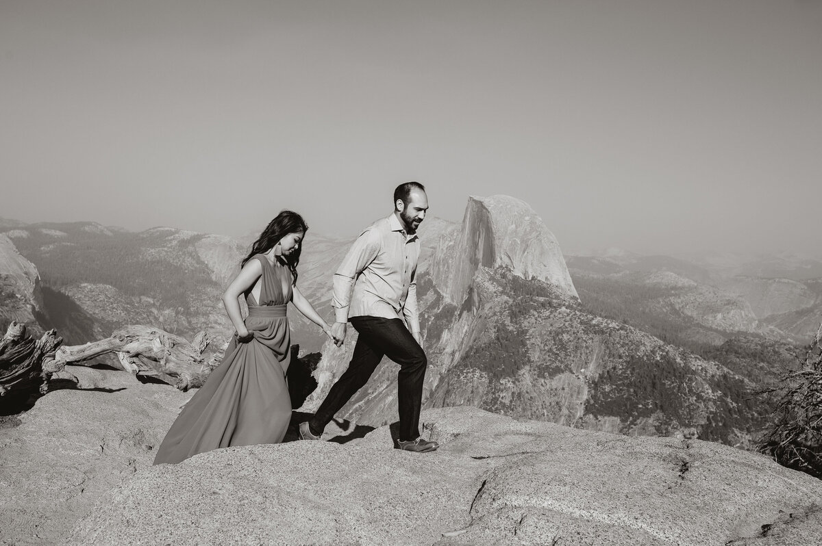 man and woman walk together along flat rocks