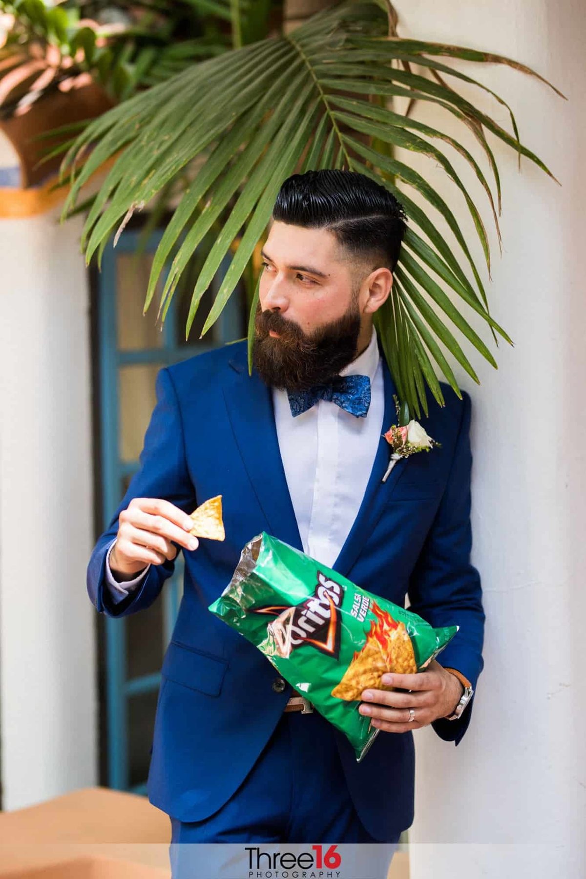 Groom is off to the side eating from a bag of Doritos prior to the wedding