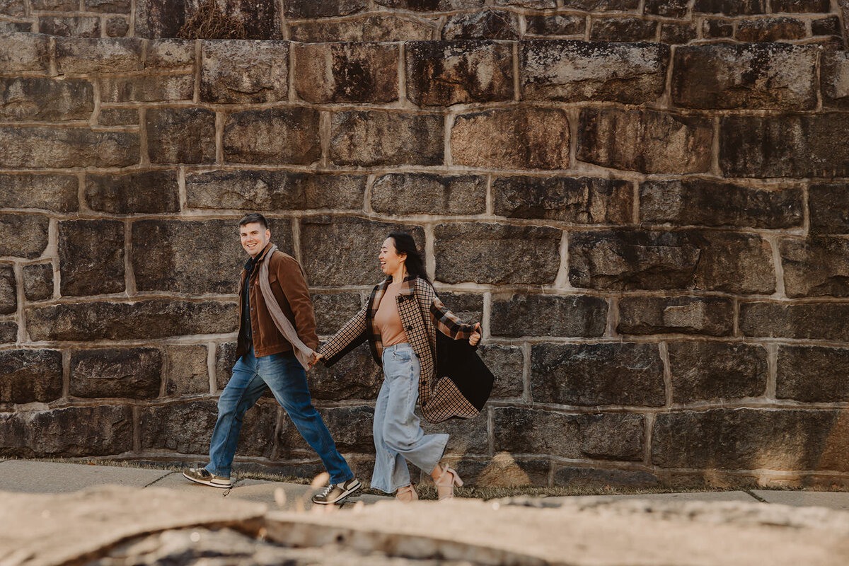 A couple holding hands and walking up a sidewalk together 