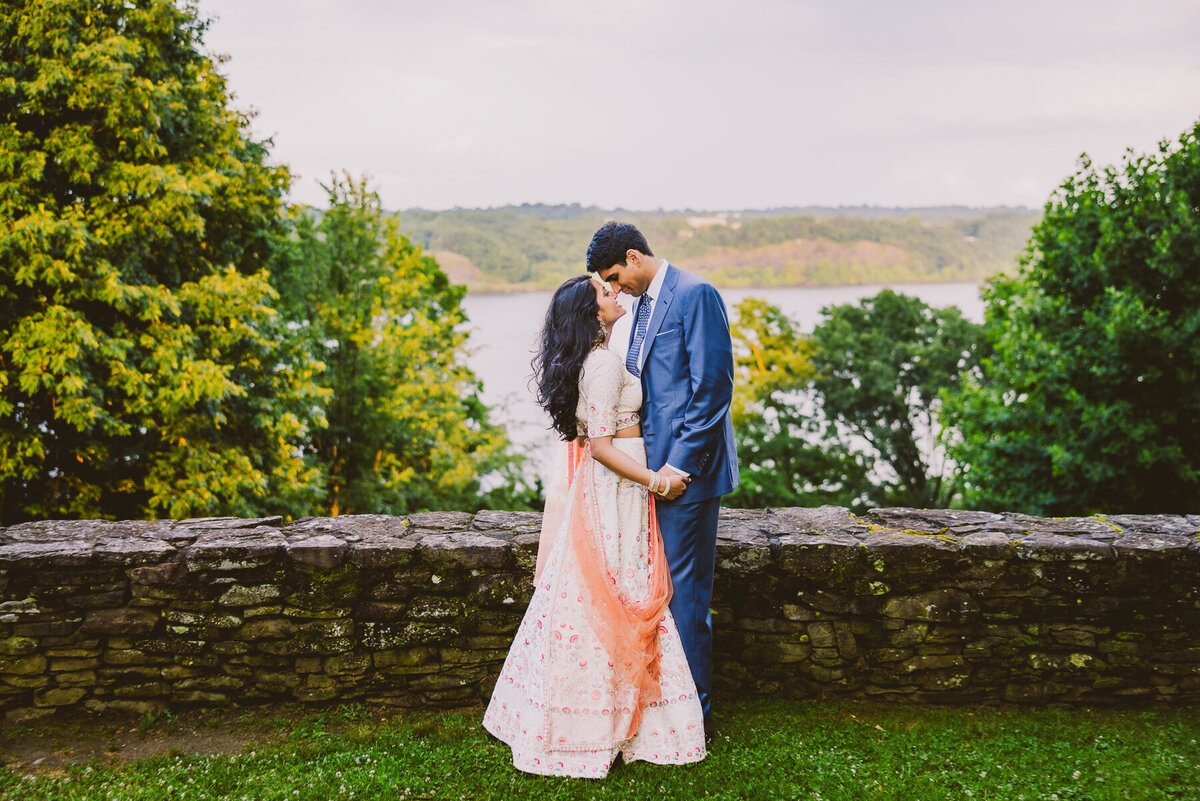 Indian wedding couple embrace with a view of the Hudson River at the buttermilk falls inn in milton ny