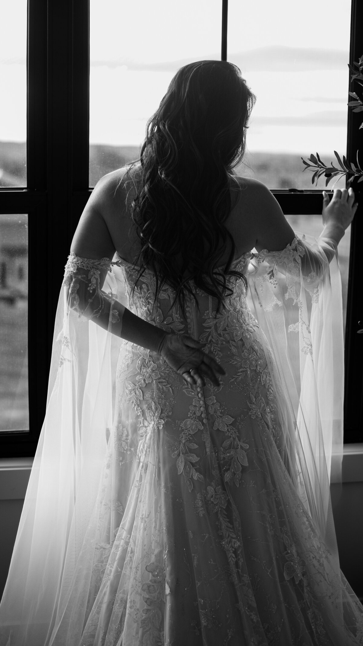 B&W Back view of bride in front of window.