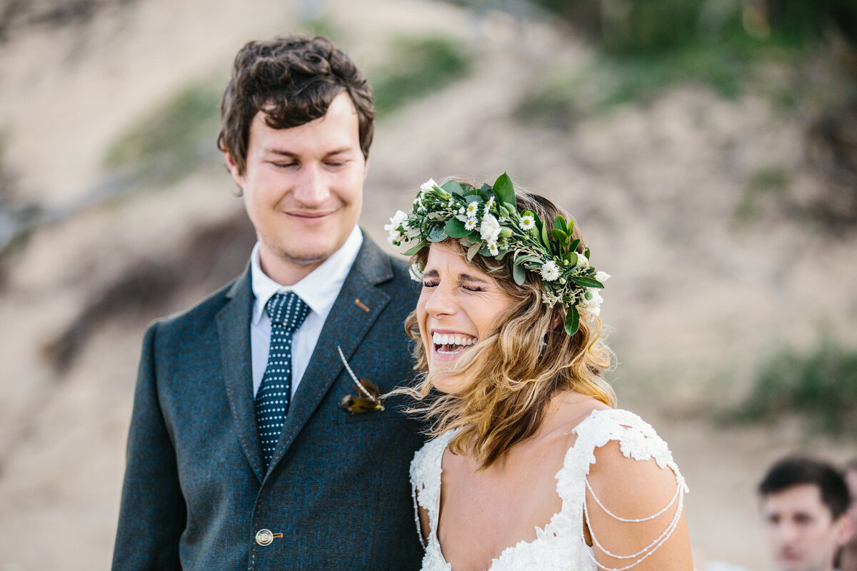 Bride belly laughs, with hair blown in the wind, documentary-style scene. 