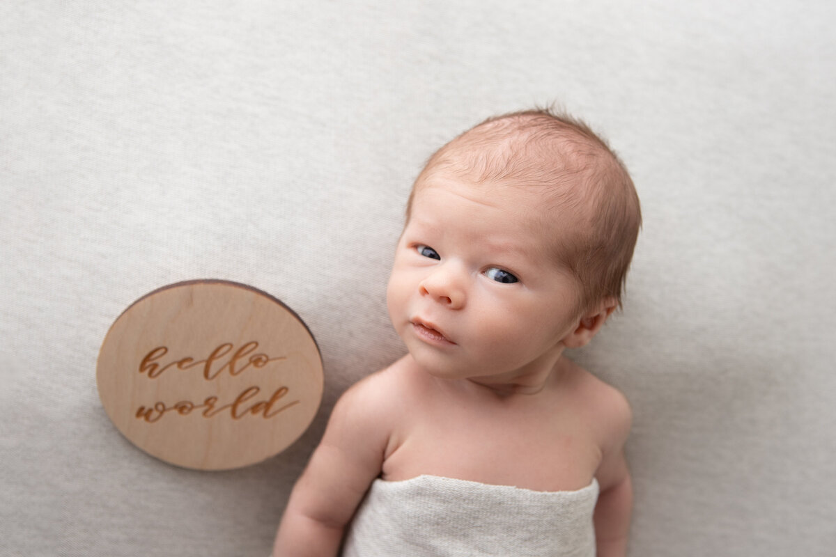 Awake newborn on a grey backdrop looking at the camera