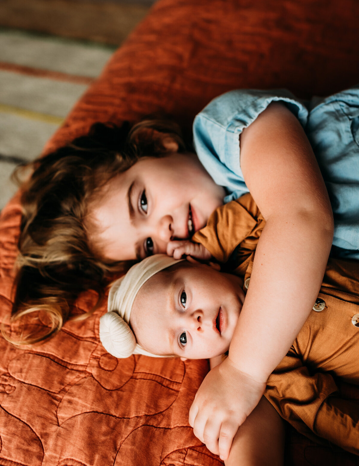 Newborn Photographer, Big sister snuggling baby sister on the bed.