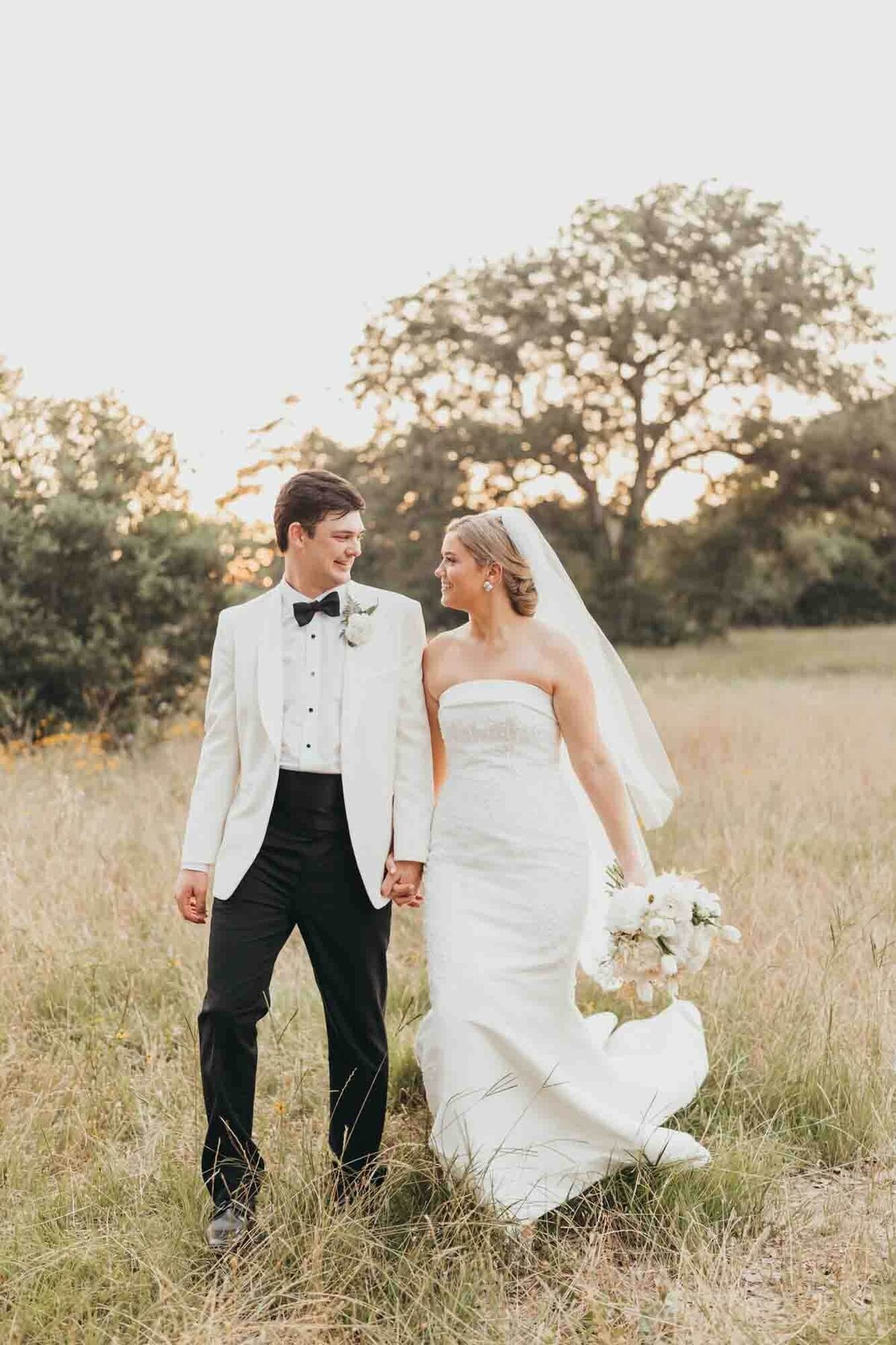 bride and groom walk side by side in a field.