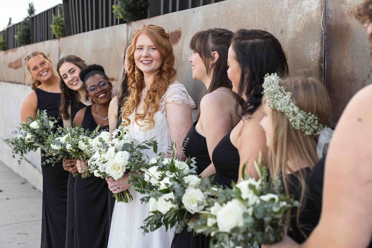 Bride smiling at camera while bridesmaids smile at her