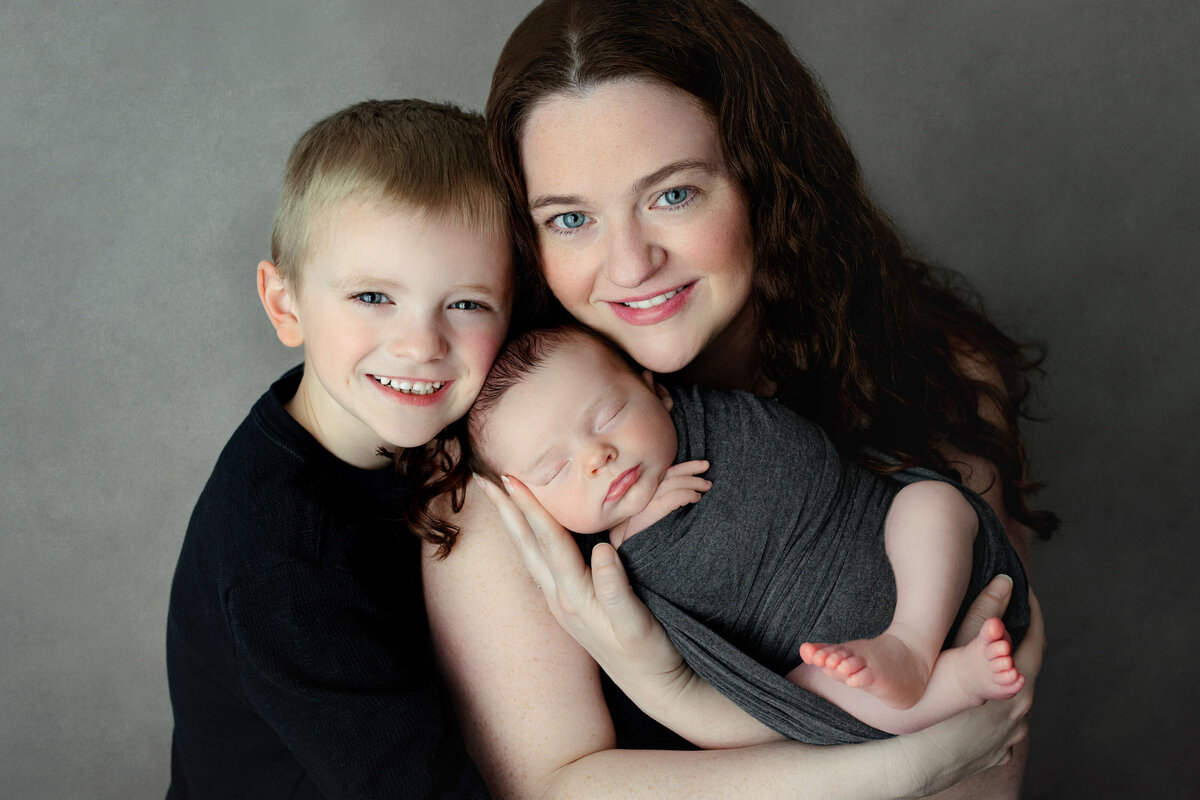 mom and her older    son holding her newborn baby boy at a newborn photo shoot in northern va