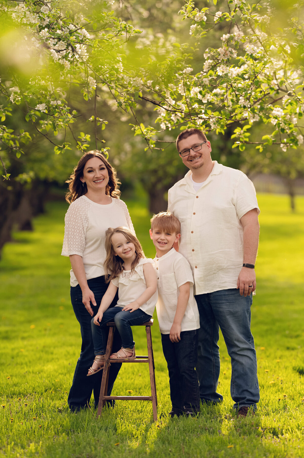 A Pewaukee family of four wears jeans and while tops for their apple orchard portraits.