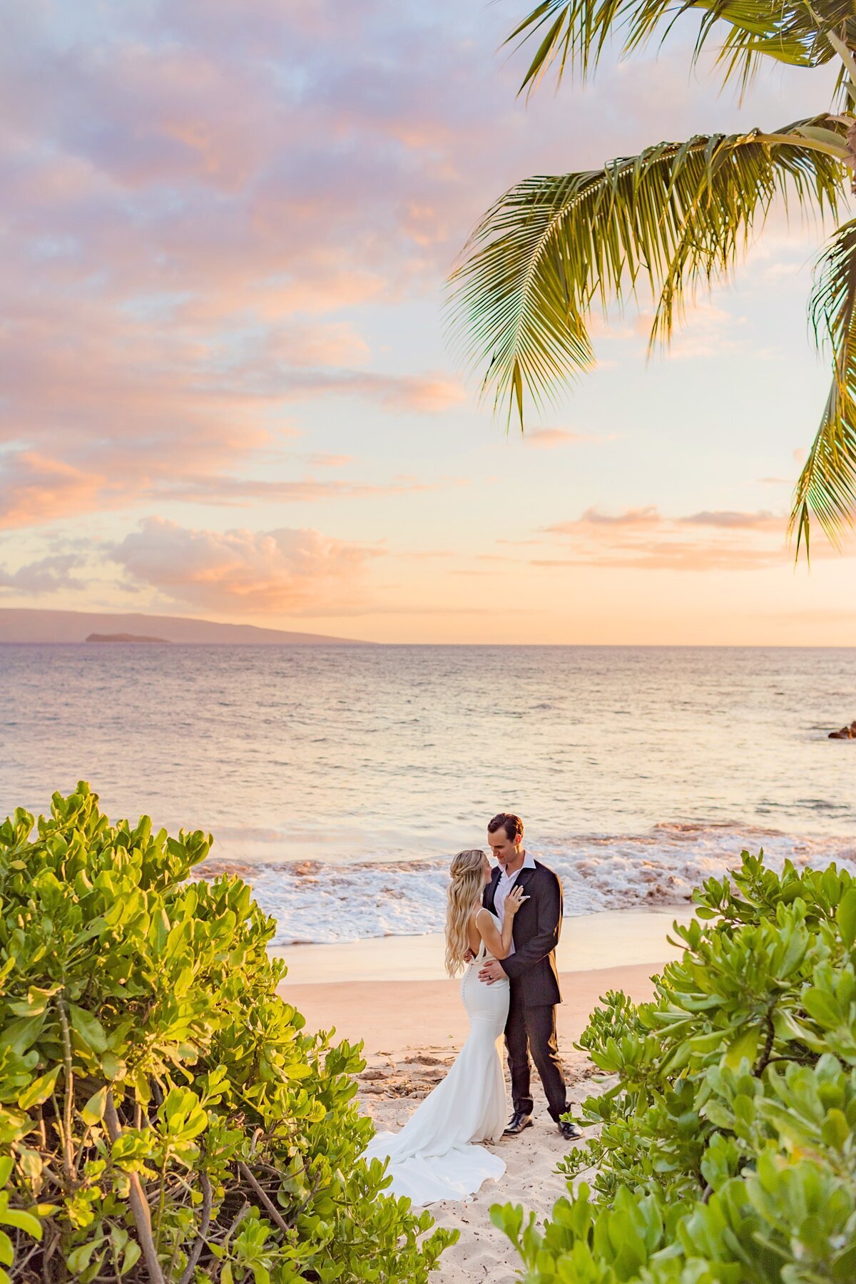 Beautiful married couple have honeymoon portraits taken on the beach at sunset in Wailea with Love + Water