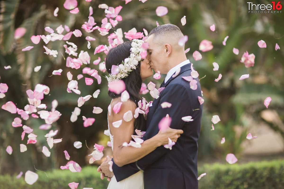 New husband and wife kiss among the flower petals