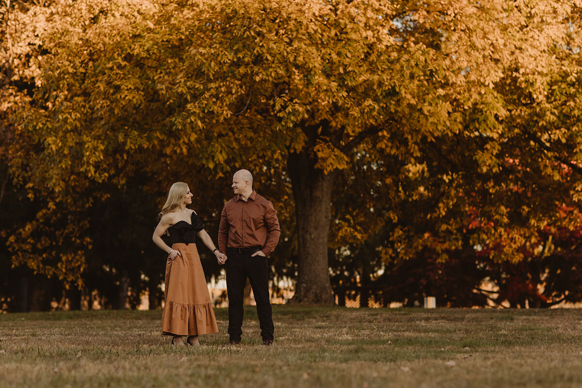 A couple holding hands in a park in fall 