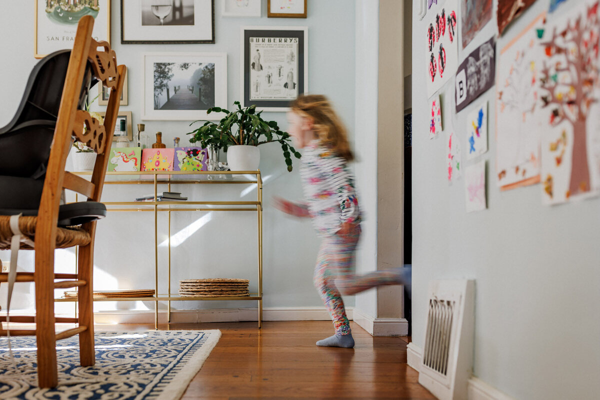 blurry photo of 5-year-old girl in mismatched clothes running through her dining room