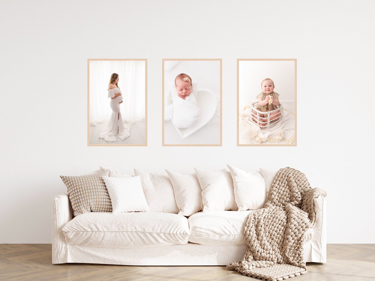 A cozy living room corner featuring an off-white sofa adorned with plush cushions and a textured throw blanket, with three framed pictures of a mother, a newborn, and an infant hanging on the wall above.