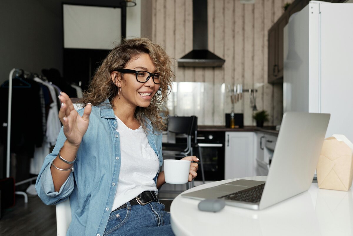 woman smiling and waving at computer