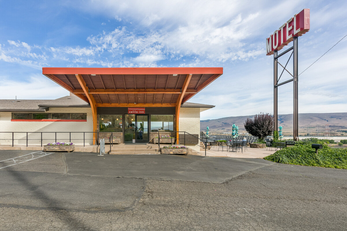 Tables with folded umbrellas, and chairs at Celilo Inn
