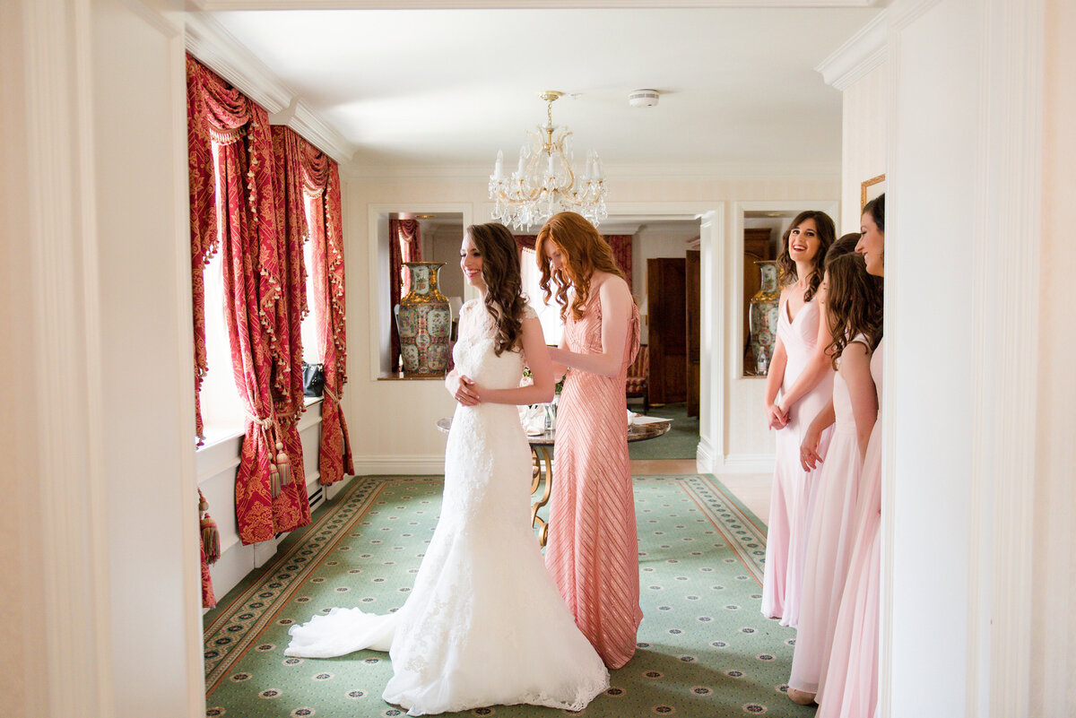 sister helping bride get ready in omni suite