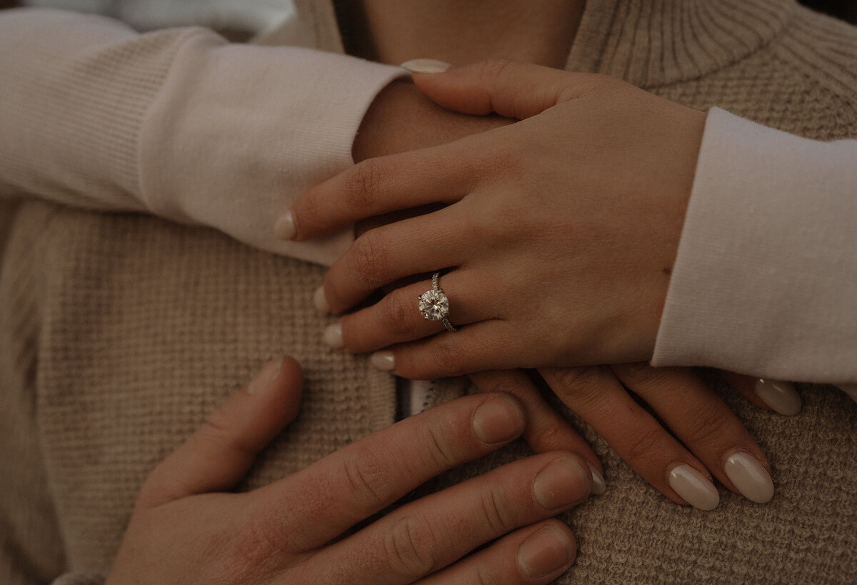 close up of engaged couple's hands and the woman's ring