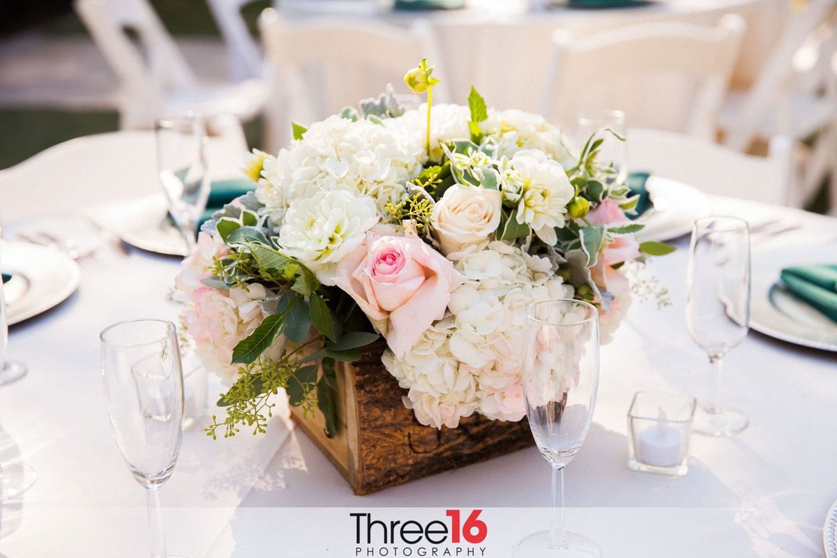 Centerpiece  comprised of flowers in a log looking holder at a wedding reception