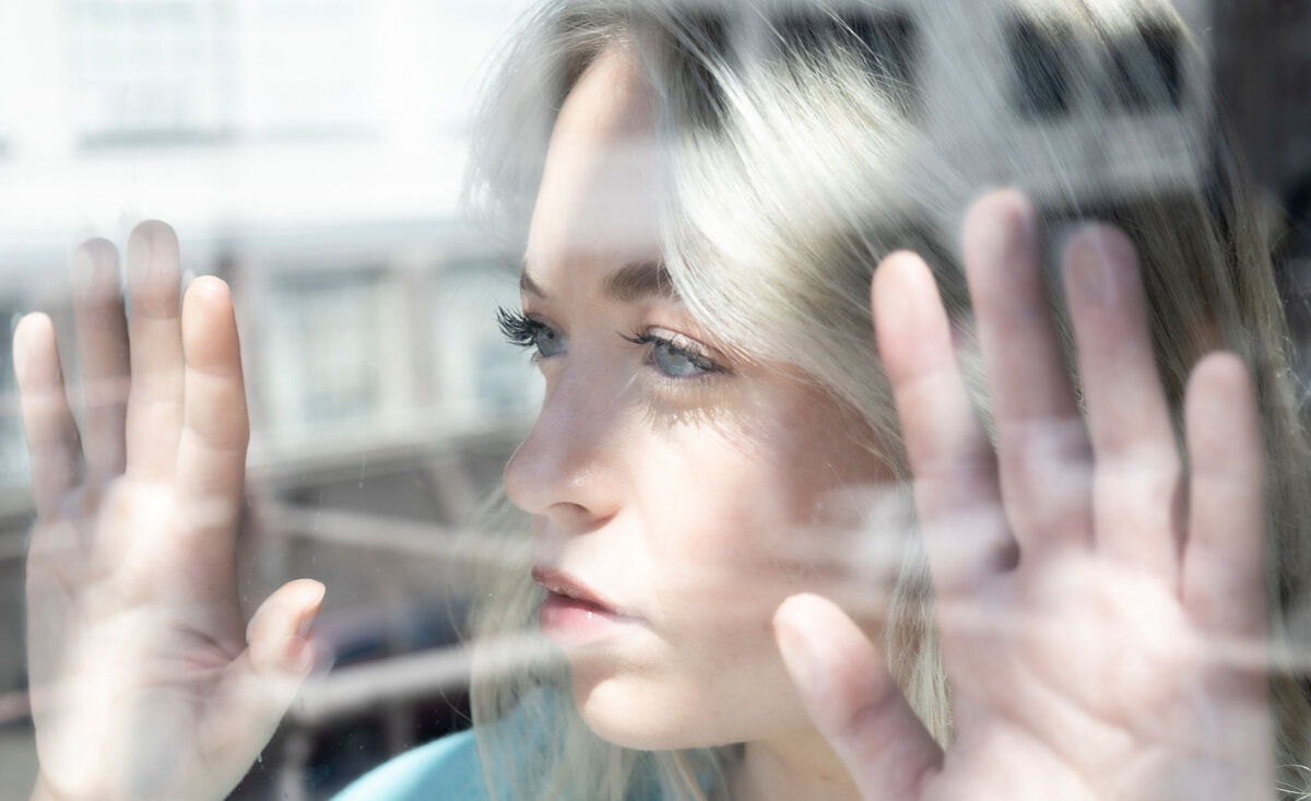 Female musician portrait Chloe DeMore  close up behind reflections  hands pressed against window