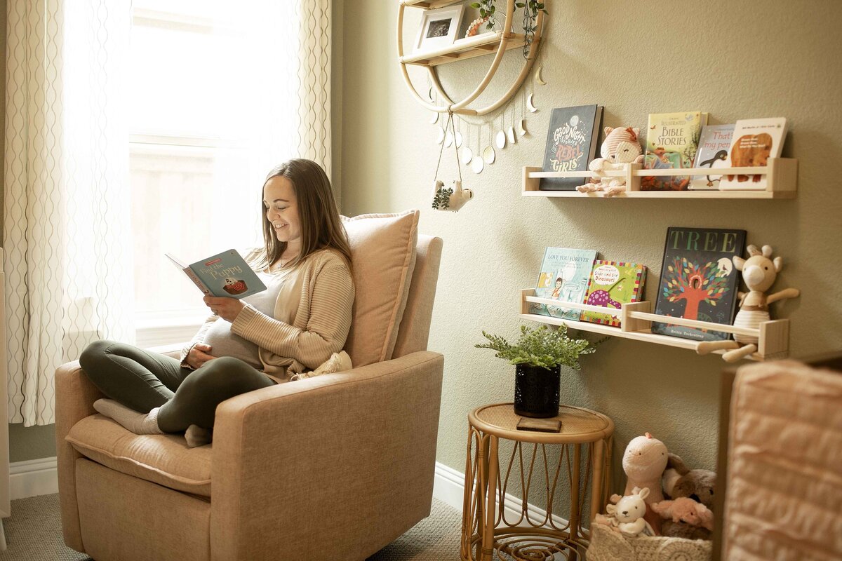 A heartwarming maternity shot of mom in the nursery, reading a book while softly resting her hand on her belly, imagining stories for her little one, captured by Chunky Monkey Photography.