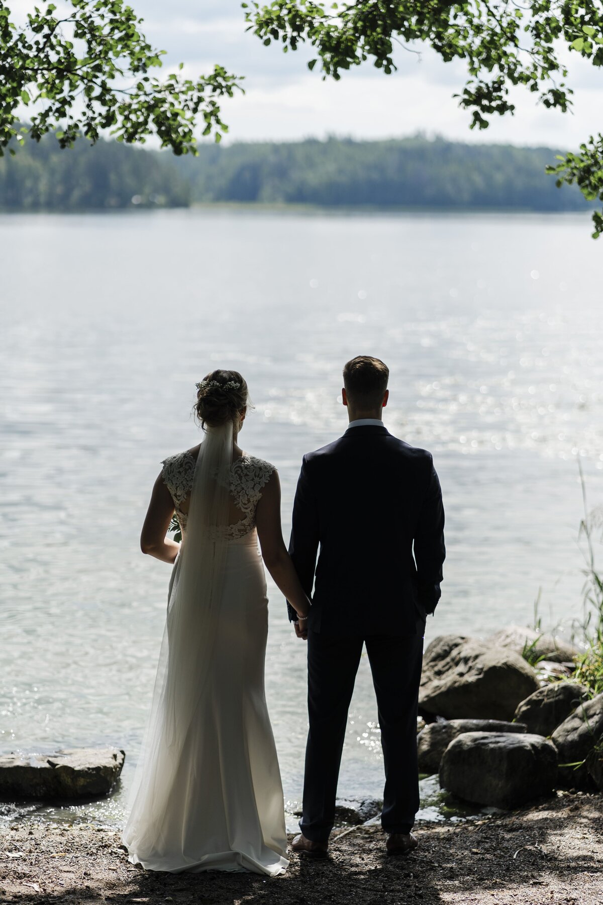 hääpari järven rannalla katsellen vettä