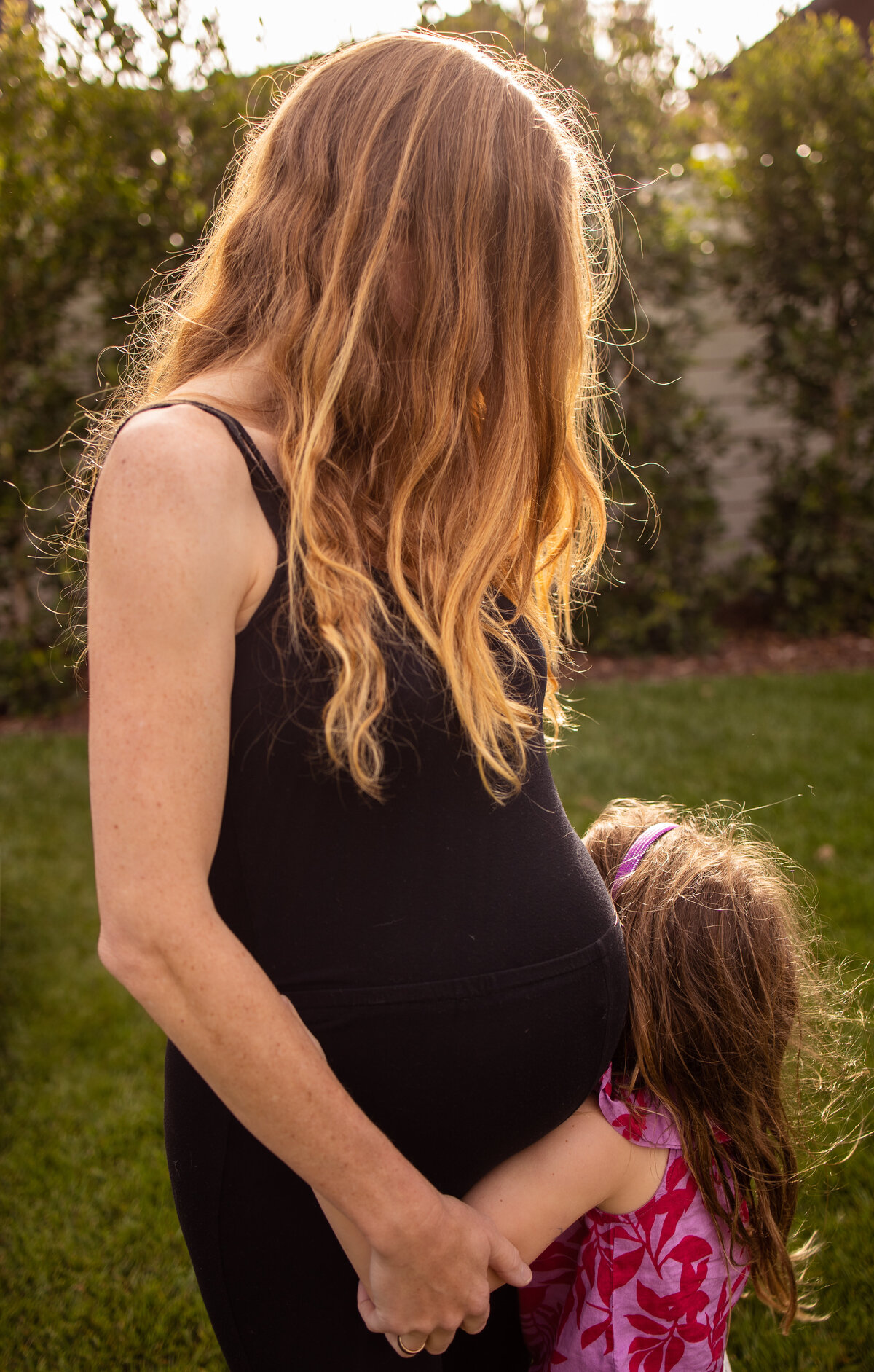 Daughter embraces mother's pregnant stomach
